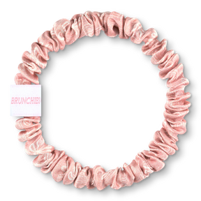Rosafarbener BRUNCHIES® x The Momence Club Seiden Scrunchie "This Mom Needs Champagne" aus 100 % Maulbeerseide mit weißen Champagnergläsern.